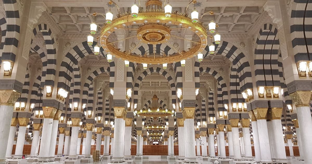 Interior view of the Grand Mosque with marble columns and golden chandeliers. Search for luxury Umrah UK, 5 star Umrah packages UK, and premium Umrah deals.