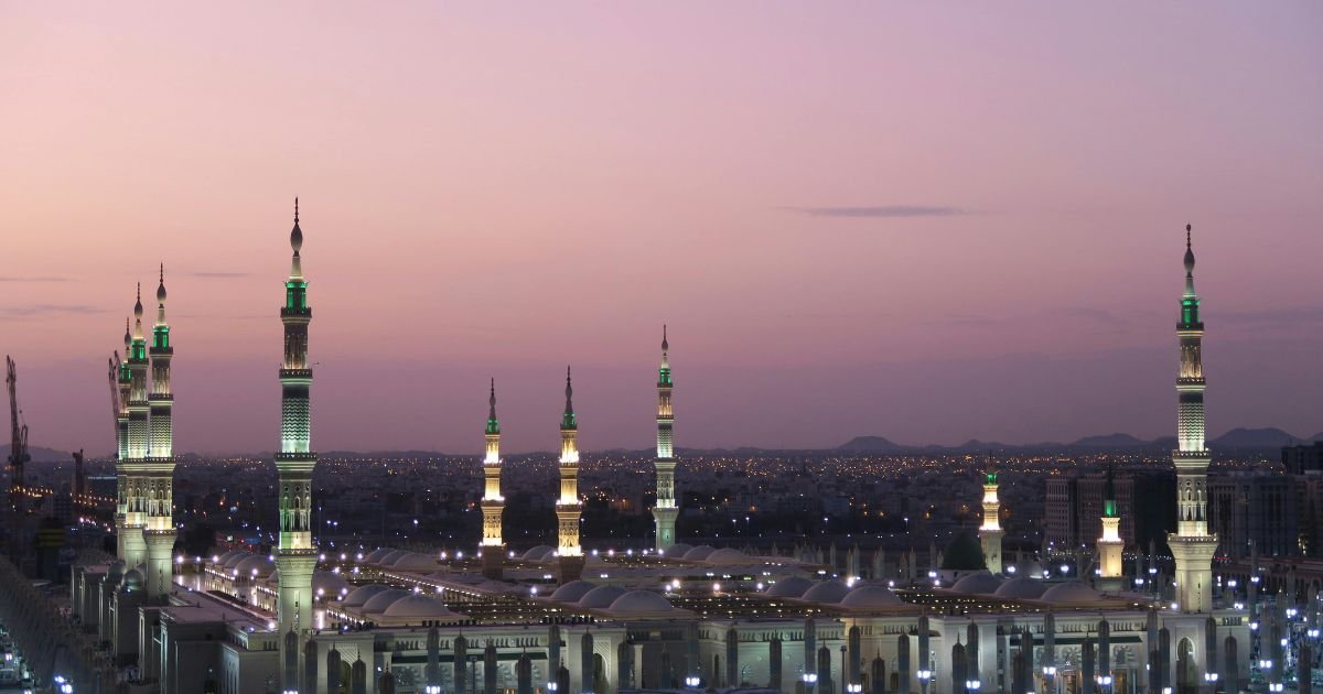 Illuminated minarets of Al-Masjid an-Nabawi in Medina at sunset. Find the best time for Umrah UK, including Umrah in Ramadan UK and off-season Umrah UK deals.