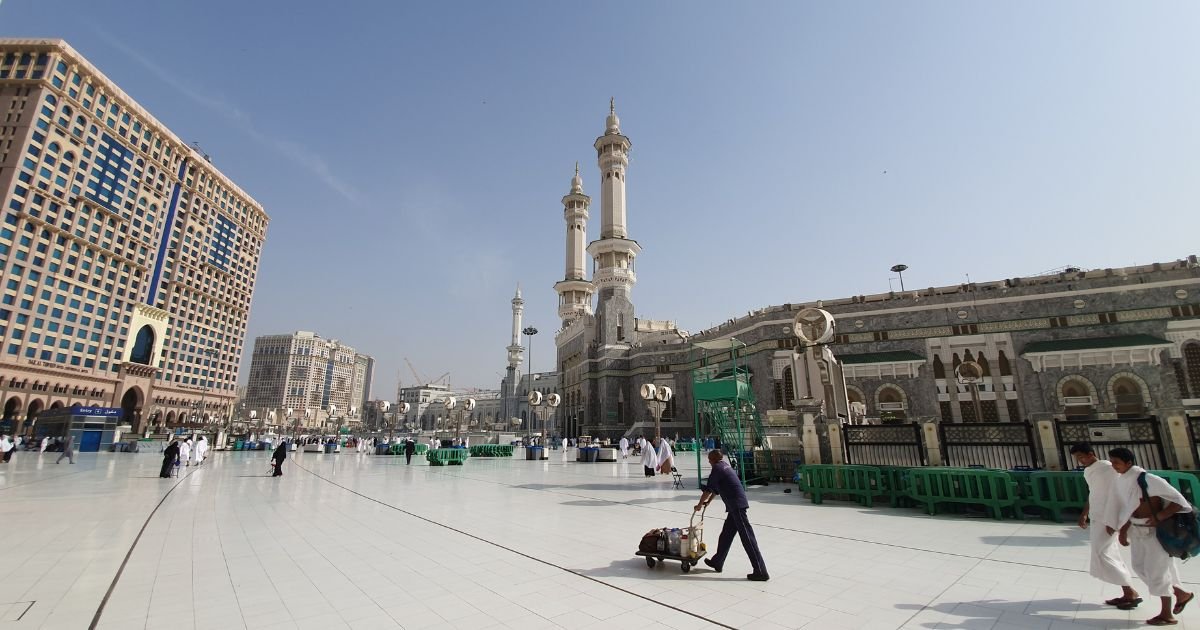View of the Grand Mosque courtyard in Mecca showing nearby modern accommodation. Perfect image for promoting 5 star Umrah packages UK, luxury Umrah UK, and affordable Umrah packages. Book your Umrah packages from UK or Umrah with kids UK for Umrah 2025 UK.