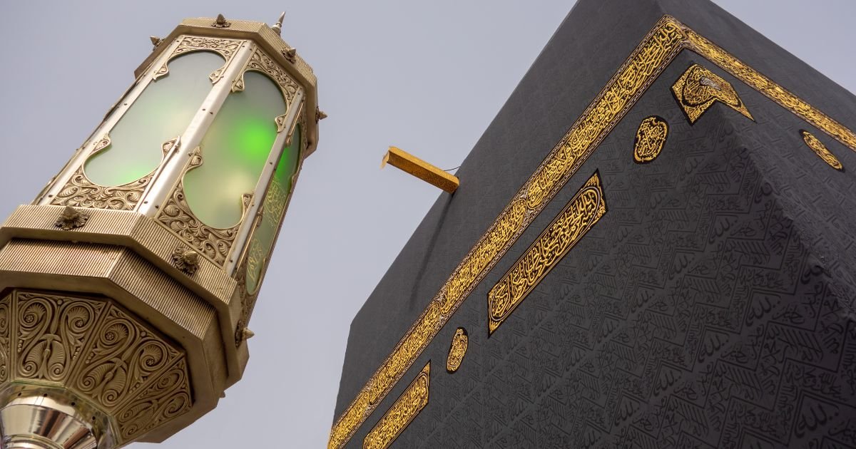 Close-up of the Kaaba Kiswah and an ornate Haram lamp. Inquire about our exclusive luxury Umrah UK packages for the best time for Umrah UK