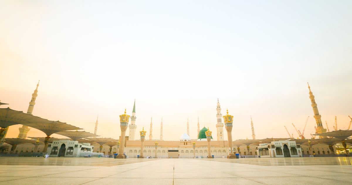 The vast, tranquil courtyard and majestic minarets of Masjid al-Nabawi in Medina at sunrise, the holy site travelers reach after meeting all Umrah visa requirements UK.